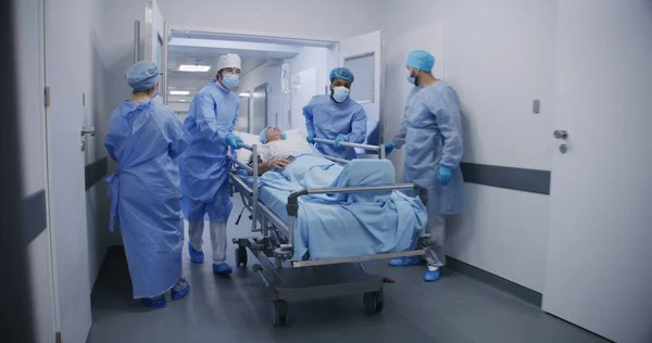 Wielokulturowi Lekarze Przewożą Starszych Pacjentów Salę Operacyjną Końcu Korytarza Kliniki — Zdjęcie stockowe