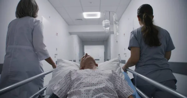 간호사가 의사는 복도를 걸어다니며 구르니 환자를 병동으로 밀어냅니다 남자는 튜브와 — 스톡 사진