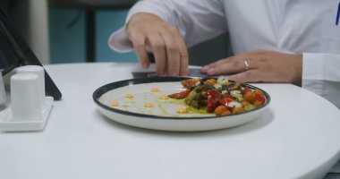 Profesyonel doktor klinikteki kafede oturur ve dijital tablet bilgisayardaki test sonuçlarını inceler. Kafeterya çalışanı sıhhiyeye yemek getiriyor. Sağlık personeli hastane veya tıp merkezi kantininde yemek yer..