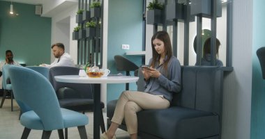 Yetişkin bir kadın modern klinik kafesinde koltukta oturur, internette telefonla sörf yapar. Kafeterya çalışanı kadın ziyaretçiye yemek getiriyor. Sağlık personeli ve hastalar sağlık merkezinin yemek salonunda yemek yiyorlar..