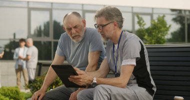 Elinde tabletle olgun bir doktor yaşlı bir hastayla bankta oturur ve ona danışır. Tıbbi üniformalı profesyonel, dijital tablet kullanan müşteriye teşhis koyuyor. Sağlık personeli dışarıda çalışıyor..