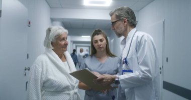 Olgun doktor klinik koridorunda yürür, meslektaş ve yaşlı hastaya gelir. Doktorlar test sonuçlarını hemşireye ve kadına gösteriyor. Hastane koridorunda tıbbi personel ve hasta var..