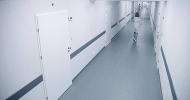 Hastane koridoru: Meşgul doktorlar, profesyonel sağlık görevlileri, hemşireler, yürüyen sağlık uzmanları. Ameliyat odaları, klinik koğuşları ve ofisler. Modern tıbbi tesiste tıbbi personel çalışıyor. Yüksek açı.
