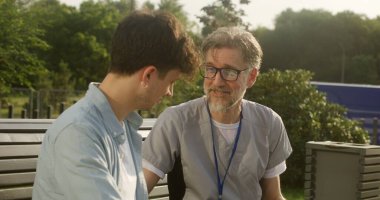 Elinde tabletle yetişkin bir doktor yetişkin bir hastasıyla bankta oturur ve ona danışır. Adam bacak ağrısından sağlık uzmanına şikayet ediyor. Doktor hastaların bacağını muayene ediyor ve dışarıda teşhis koyuyor..