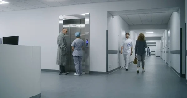 환자를 간호사는 복도에서 엘리베이터를 기다립니다 아프리카계 미국인 의사는 휠체어로 복도를 — 스톡 사진