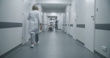 Profesyonel doktorlar yaşlı hastaları tekerlekli sandalyeyle sağlık odasına götürüp test sonuçlarını tartışırlar. Olgun doktor, meslektaşı ve kıdemli bayan için kapıyı açar. Tıbbi personel iş başında..