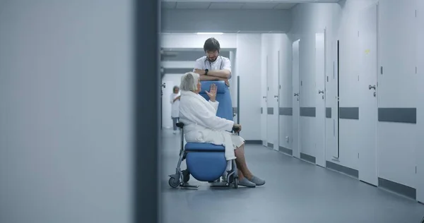 의사는 클리닉 복도에서 휠체어에 환자와 의사는 수술실 노인과 대화합니다 의료진 — 스톡 사진