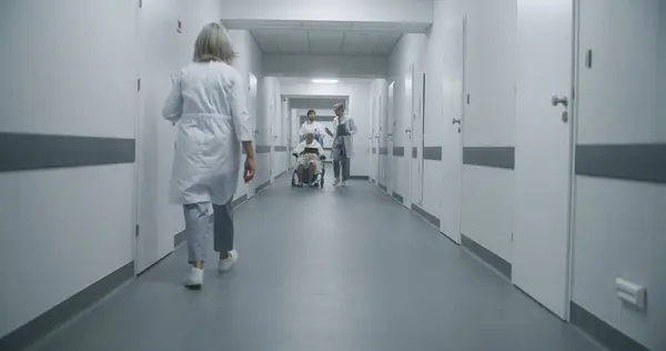 Professionelle Ärzte Transportieren Ältere Patienten Rollstuhl Den Behandlungsraum Und Besprechen — Stockfoto