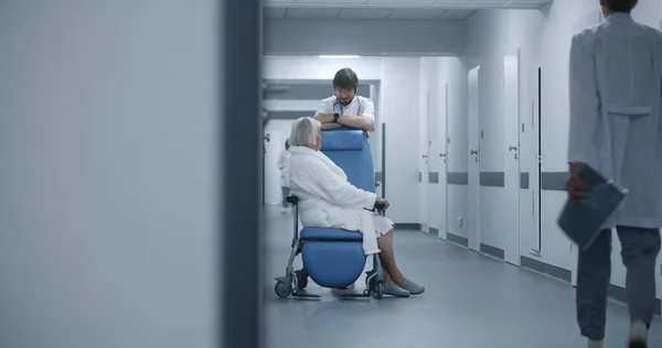 Erkek Doktor Klinik Koridorunda Tekerlekli Sandalyedeki Kadın Hastayla Birlikte Duruyor — Stok fotoğraf