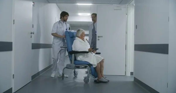 의사는 휠체어의 수술실이나 수술실에서 여성을 데려갑니다 남자는 방으로 복도를 진료소 — 스톡 사진
