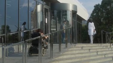 SMA engelli bir kadın elektrikli sandalyeyle kliniğe giriyor. Sağlık çalışanı kadın hastayla tanışır, döner kapılardan girmesine yardım eder. Hastane ya da modern tıp merkezi dışında..