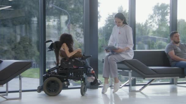 Femme Fauteuil Roulant Parle Médecin Dans Hôpital Moderne Hall Clinique — Video
