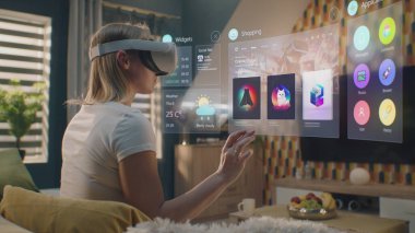VR kulaklıklı kadın evde takılan kıyafetleri internetten seçiyor. 3D fütüristik hologram, kullanıcı menüsü ve giyim mağazası web arayüzündeki gereçleri gösteriyor. VFX animasyonu. Çevrimiçi alışveriş kavramı.