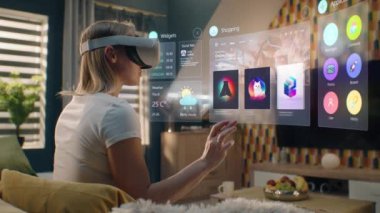 VR kulaklıklı kadın evde takılan kıyafetleri internetten seçiyor. 3D fütüristik hologram, kullanıcı menüsü ve giyim mağazası web arayüzündeki gereçleri gösteriyor. VFX animasyonu. Çevrimiçi alışveriş kavramı.