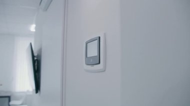 Hastane odasındaki duvarda asılı siyah beyaz saat. Minimalist tasarımı olan elektronik saat tarih ve zamanı gösteriyor. Arka plandaki duvarda asılı siyah televizyon. Klinikte modern ekipman.