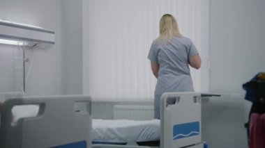 Yetişkin sağlık çalışanları hastane koğuşundaki yataklar arasında yerleri paspaslıyor. Olgun temizleyici yataklarda çarşaf değiştirir. Hemşireler yeni hastalar için hastane odasını temizler. Modern klinikte çalışan tıbbi personel.