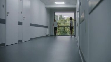 Afrikalı Amerikalı çocuk arkadaşıyla tokalaşıyor. Kırık bacağı olan beyaz bir genç bir genci daha bırakıp klinik koridorunun aşağısındaki hastane koğuşuna gidiyor. Modern tıp merkezindeki hastalar.