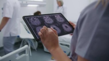 Olgun doktor Afro-Amerikan ergenlerle konuşuyor. Hasta hastane koğuşunda yatakta yatıyor. Kadın doktor MR veya CT tarama sonuçlarını dijital tablet bilgisayardan öğrenir. Modern klinikte çalışan tıbbi personel