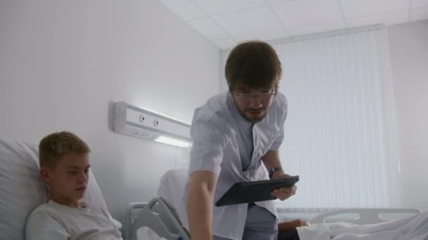 Médecin Avec Tablette Dans Les Mains Contrôle Jeune Garçon Pose — Video