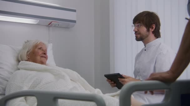 Ärztin Konsultiert Ältere Patientin Die Krankenhauszimmer Bett Liegt Männlicher Arzt — Stockvideo