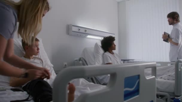 Νοσοκόμα Επιδέσμους Πόδι Του Νεαρού Αγοριού Ξαπλωμένο Στο Κρεβάτι Γιατρός — Αρχείο Βίντεο