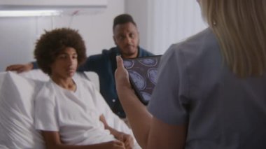Doktor X-Ray sonuçlarını tablet bilgisayar kullanan hastalara bildiriyor. Afro-Amerikalı ergen yatağa uzanıp doktorla konuşuyor. Hasta ameliyattan sonra iyileşiyor. Hastane koğuşunda tıbbi personel.