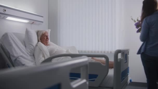 老年女性病人躺在明亮的病房里躺在床上休息 爱家探访成功手术后康复的老奶奶 现代医疗设施或诊所 — 图库视频影像