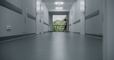 Afro-Amerikalı genç sporcu kliniğin koridorunda tek başına pencereden dışarı bakıyor.