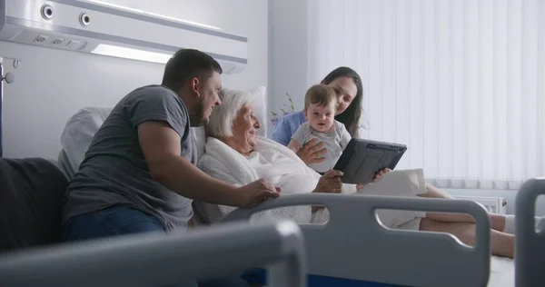病院の部屋 愛する家族は 手術が成功した後に回復する高齢のおばあちゃんをサポートします デジタルタブレットを使用したビデオ通話による親戚の話 一緒に時間を過ごす 現代医療施設 クリニック — ストック写真