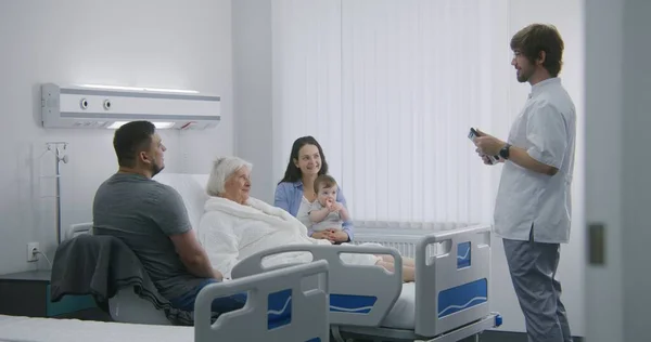 환자는 방에서 침대에 가족과 시간을 보낸다 간호사 의사는 디지털 태블릿을 — 스톡 사진