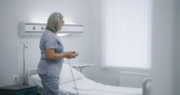 Gammal Sjuksköterska Ställer Sängen Med Fjärrkontroll Förbereder Sjukhusrum För Patienten — Stockfoto