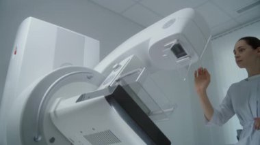 Hastane radyoloji odası. Profesyonel kadın doktor mammografi tarama işleminden önce dijital mammografi makinesini ayarlar, sonra da bilgisayar kullanır. Göğüs kanseri önleme. Modern klinik ekipmanı.
