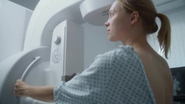 Kafkasyalı yetişkin kadın hastanenin radyoloji odasında duruyor. Mamografi çekilen kadın hasta dijital mammografi makinesi kullanıyor. Göğüs kanseri önleme. Modern klinik ekipmanı.
