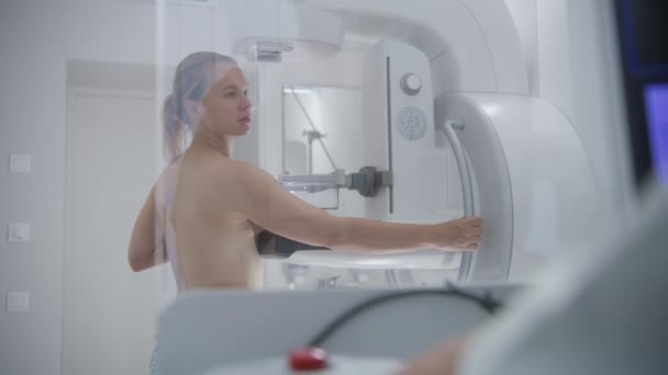 在医院放射科检查期间 成年妇女赤身裸体站立 医生按下控制面板上的按钮 用计算机启动乳房X光照相机 乳腺癌的预防 — 图库视频影像
