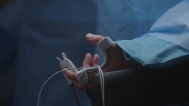 Erkek hasta ameliyat odasında anestezi altında yatıyor. Cerrahlar zor bir ameliyat yapar. Tıbbi sensörleri ve nabız ölçeri olan bir adama yaklaş. Klinikte ya da hastanede modern ekipman.