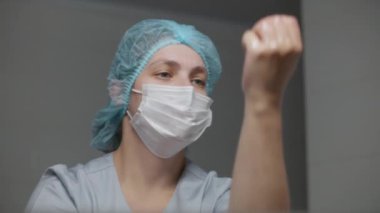Üniformalı bir cerrah ameliyattan önce ellerini yıkar ve aynaya bakar. Kadın doktor ciddi şekilde yaralanmış bir hastaya ameliyat yapmaya hazırlanıyor. Modern tıbbi tesiste personel işleri..