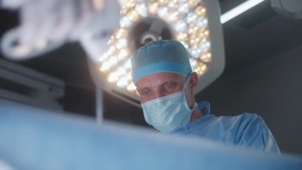 使用腹腔镜器械进行手术的专业外科医生的近视 手术灯照亮了重伤员的手术台 医疗设施的人员工作 — 图库视频影像