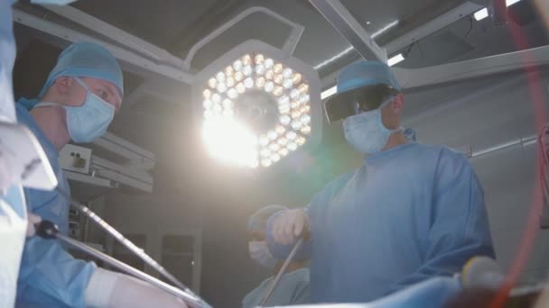 一组戴防护眼镜的外科医生在手术中使用腹腔镜检查工具 医生和医护人员对严重受伤的病人进行外科手术 在现代医院工作的医务人员 — 图库视频影像