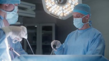 Cerrahlar kalp nakli sırasında laparoskopik aletler kullanır. Doktorlar ve sağlık görevlileri ciddi şekilde yaralanmış bir hastaya ameliyat yapıyorlar. Tıbbi personel modern ameliyathanede çalışıyor..