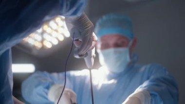 Yetişkin erkek cerrah monitöre bakar ve meslektaşlarıyla birlikte hastayı ameliyat eder. Profesyonel doktorlar ameliyathanede ameliyat sırasında modern laparoskopi aletleri kullanırlar. Klinikte çalışan tıbbi personel.