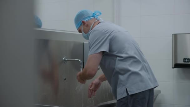 外科医生穿着制服 在手术前洗手 辅助医务人员或医生准备对严重受伤的病人进行外科手术 现代医疗设施的人员工作 — 图库视频影像
