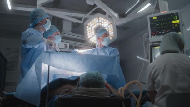 护士用心电图监测器检查病人的病情 成年男子躺在桌子上麻醉 专业的外科医生进行腹腔镜检查并检查监视器 内科手术室 — 图库视频影像