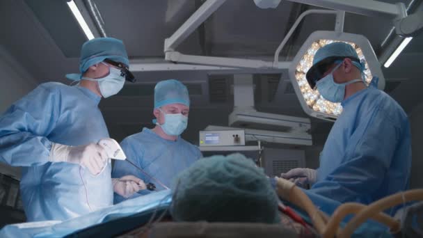 一组戴防护眼镜的外科医生在外科手术中使用腹腔镜检查工具 医生和医护人员对病人进行心脏移植 在现代医院工作的医务人员 — 图库视频影像