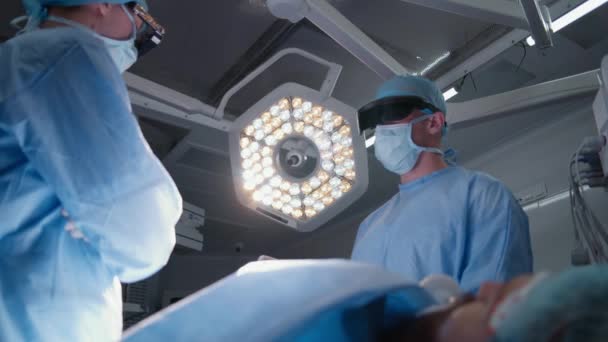 Команда Хирургов Защитных Очках Стоит Стола Пациентом Обсуждает Процесс Операции — стоковое видео