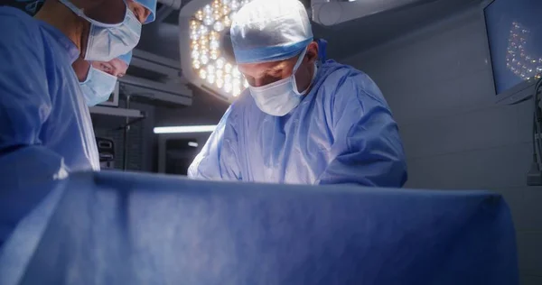 男外科医生为成年患者做手术 护士协助医生并提供医疗工具 男人躺在桌子上 在麻醉下有呼吸管 在设备齐全的手术室工作的医务人员 — 图库照片