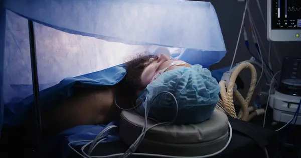 手术过程中病人的近视 在现代手术室里 成年男子躺在桌子上 全身麻醉 有呼吸管 专业外科医生用腹腔镜器械给病人做手术 — 图库照片