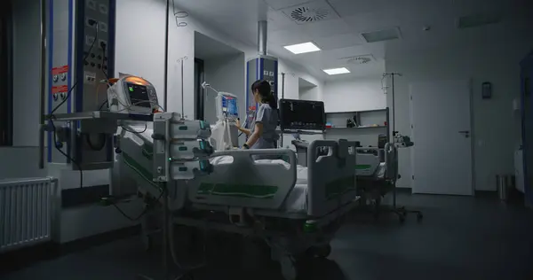 病院に近代的な設備を備えた緊急治療室 酸素マスクの高齢者は 手術が成功した後にベッドで眠る 看護師は医療施設の集中治療部門でコンピュータで働いています — ストック写真