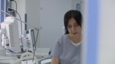 Dost canlısı hemşire konuşur ve oksijen maskesi takan yaşlı hasta ile ilgilenir, hastane monitörü kullanır. Klinikte modern ekipmanlarla acil servis. Tıp merkezindeki yoğun bakım bölümü..