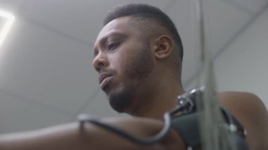 Afrikalı Amerikalı adam, elektrokardiyografi ya da kan basıncı ölçümleri sırasında kardiyoloji odasında tonometre pedallı hasta. Modern hastanede işlevsel rehabilitasyon. Portre.