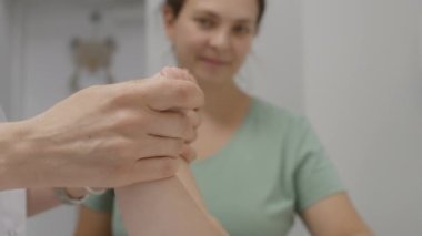 Kalça eklemi gelişimini kontrol eden kadın doktorlara yakın çekim. Küçük çocuk hafif hastane koğuşunda masasını değiştiriyor. Anne ayağa kalkar ve çocuğunu çocuk doktoruyla randevusuna götürür..